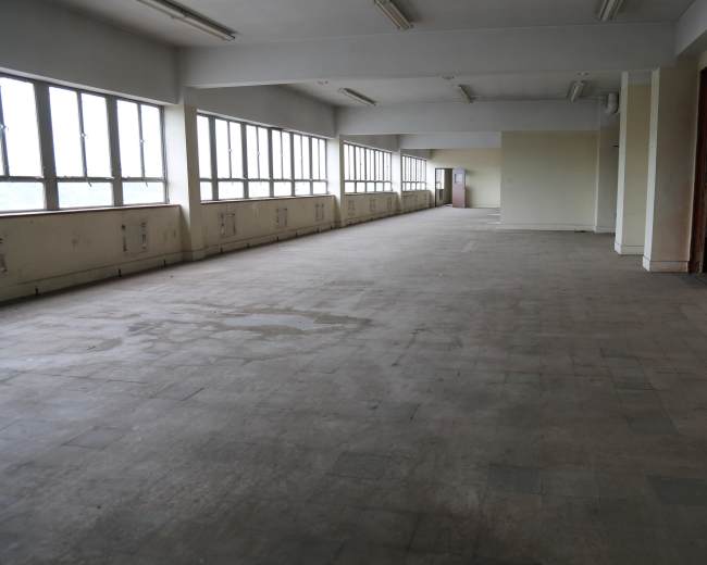 A spacious, empty room with large windows and a bare floor.