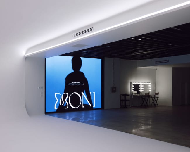 A large screen displays a silhouette against a blue background in a modern, minimalistic studio space.