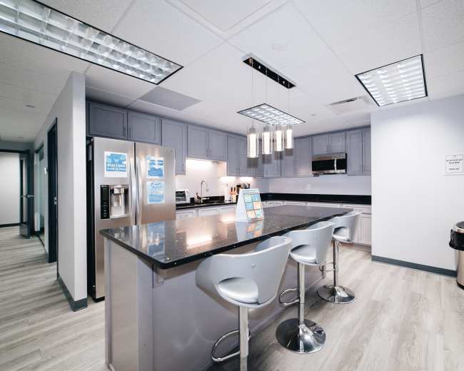 The kitchen features modern gray cabinetry, a large island with seating, and stainless steel appliances.