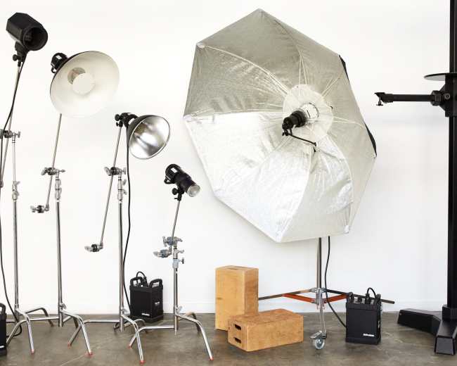 Various photography lighting equipment, including softboxes and light stands, positioned against a plain wall.