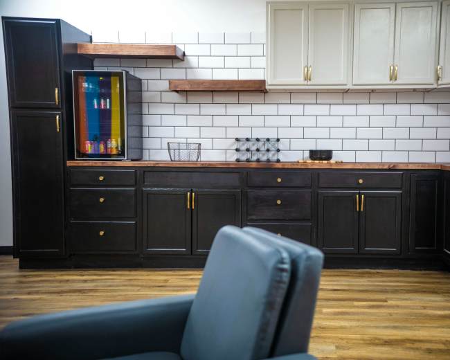The image shows a modern kitchen with dark cabinetry, a wooden countertop, and white subway tile backsplashes.
