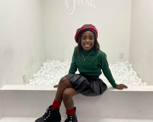 A girl sits on a ledge in a white room with a sign reading "Splash N Dash" above her, surrounded by white balls on the floor.