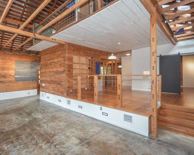 An open-concept room with wooden walls, exposed beams, and a concrete floor.