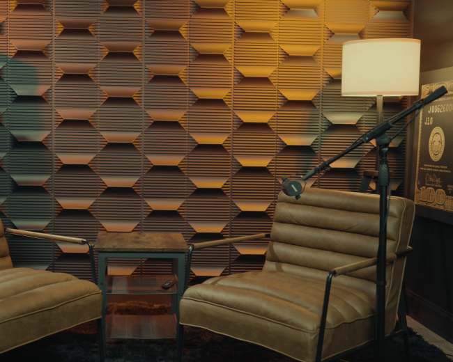 The image shows two leather chairs facing each other in a room with a textured hexagonal wall and a small table between them.