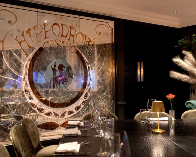 The image shows the interior of a restaurant with a decorative glass partition featuring the words "Hippodrome Casino" and a horse illustration.