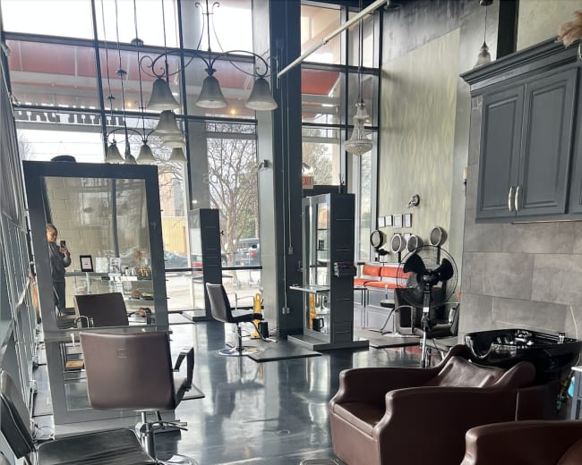 The image shows a modern hair salon with several styling chairs, shampoo stations, and large windows allowing natural light to fill the space.