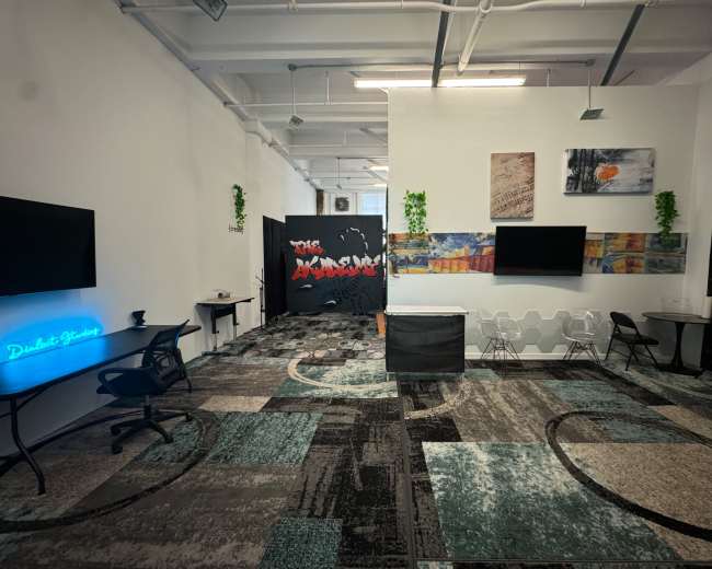 A modern office space featuring a combination of seating areas, decorative wall panels, and two large screen displays.