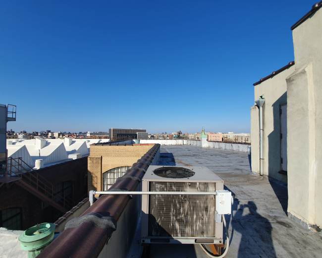 A rooftop scene with an air conditioning unit and a clear blue sky in the background.
