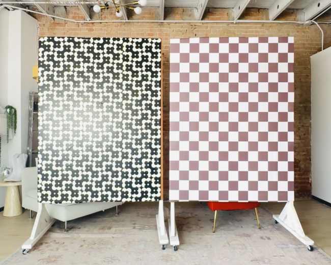 The image shows two large panels on wheels; one features a black and white patterned design, while the other displays a red and white checkered pattern.