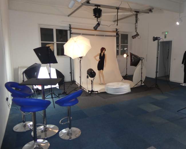 A photography studio is set up with lighting equipment and a mannequin on a white backdrop.