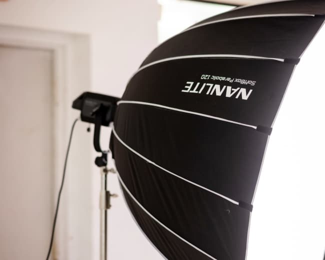 A softbox lighting setup is positioned on a stand in a bright room.