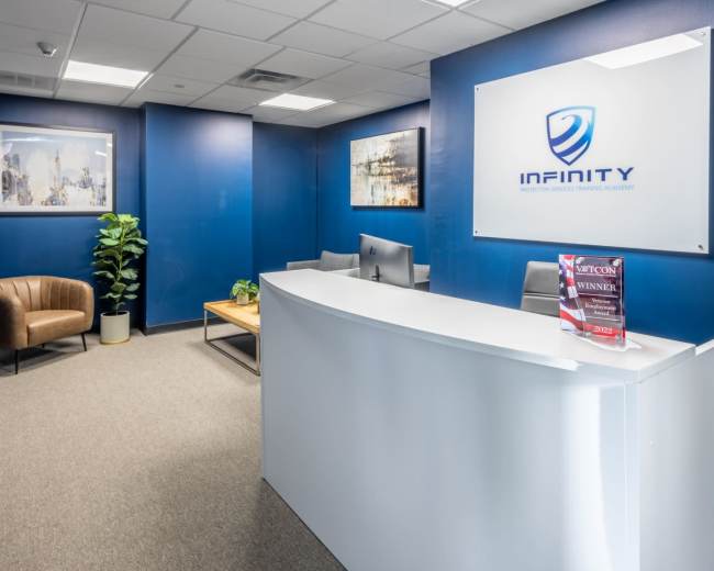 The image shows a modern reception area with a white desk, a brown chair, and blue walls adorned with framed artwork.