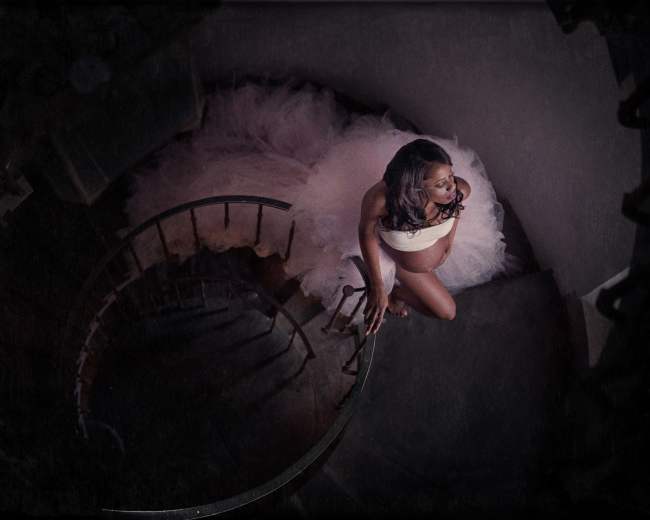 A woman in a white wedding dress ascends a spiral staircase.