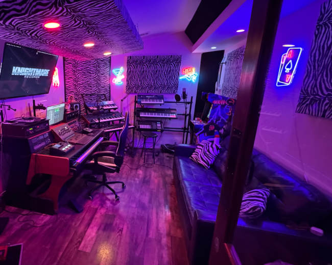 The image depicts a vibrant music studio decorated with zebra-striped walls, neon lights, and various musical equipment arranged around a central workstation.