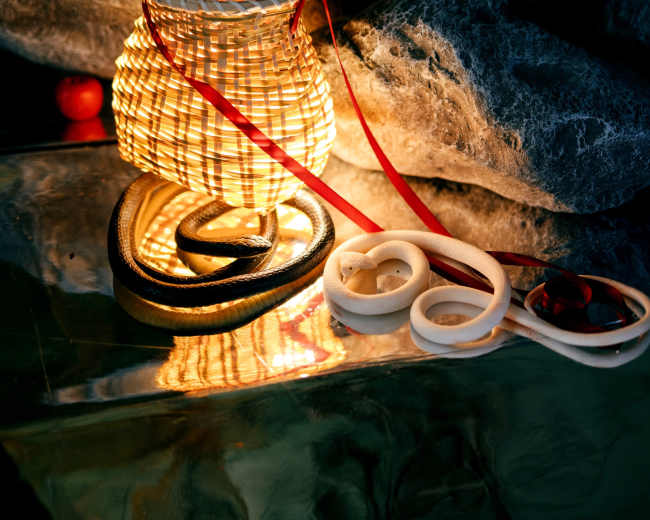 A woven basket emits light and is surrounded by rocks and various decorative items.