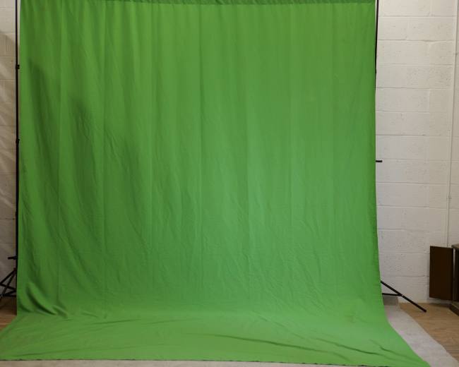 A large green backdrop set up in a studio environment.