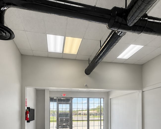 The image shows a spacious, empty commercial interior with large windows and a modern ceiling design.