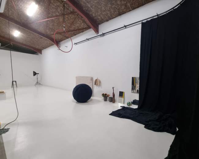 A spacious studio with a black curtain, a circular object, and various props arranged against a white wall.