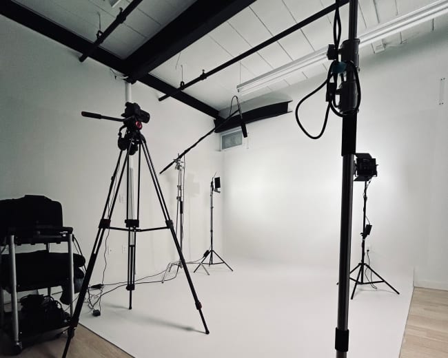 A photography studio set up with tripods, lighting equipment, and a clean white backdrop.