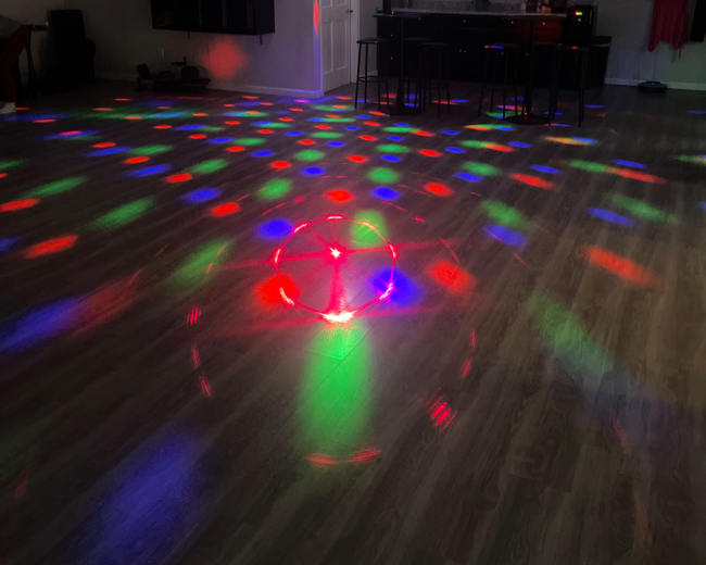 A brightly lit dance studio features colorful lights projecting patterns on the floor and walls.