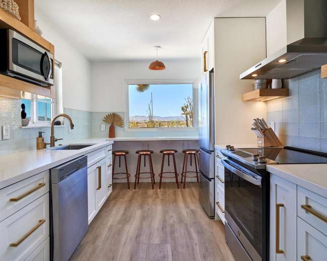 A modern kitchen features stainless steel appliances, white cabinetry, and a window with a view of the outdoors.
