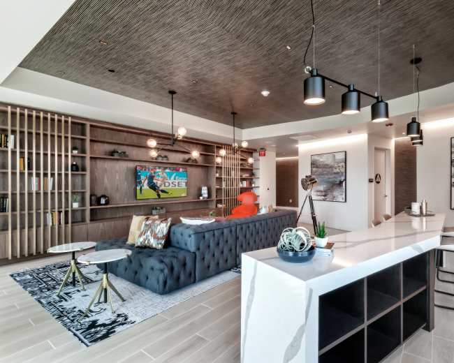 The image shows a modern living space with a sectional sofa, a sleek kitchen island, and decorative art pieces on the walls.