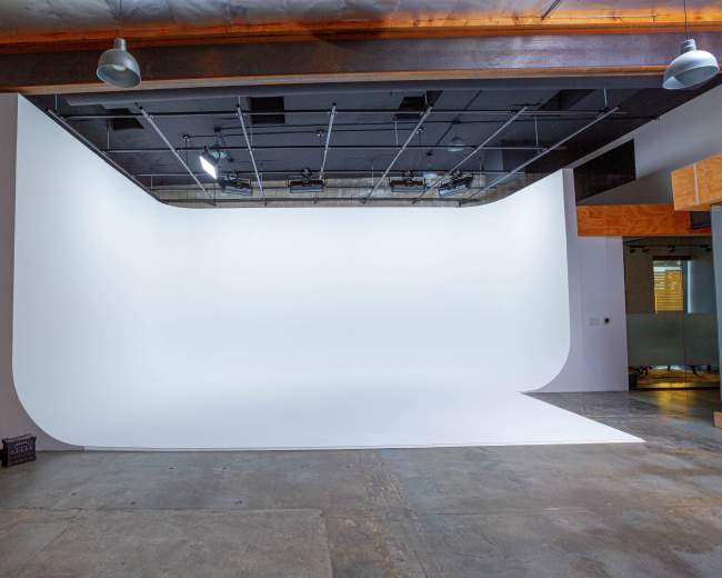 A blank photography studio with a smooth white backdrop and polished concrete flooring.
