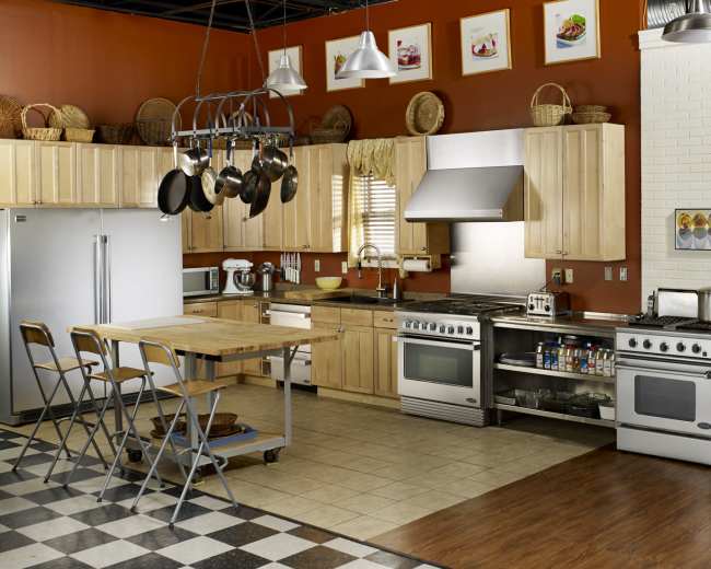 A modern kitchen features wooden cabinets, stainless steel appliances, and a large island with seating, arranged in a functional layout.