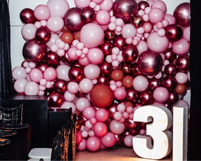 A colorful balloon installation in various shades of pink and burgundy, with a large white number "31" displayed in front.