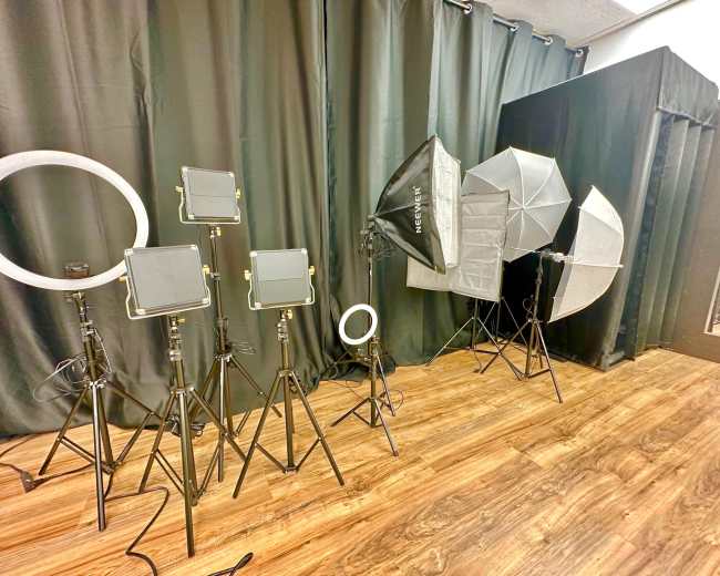 A variety of photography lighting equipment arranged on tripods against a black backdrop.