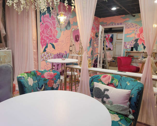 The scene features a brightly colored café with floral-themed decor, elegant seating, and artistic wall murals.