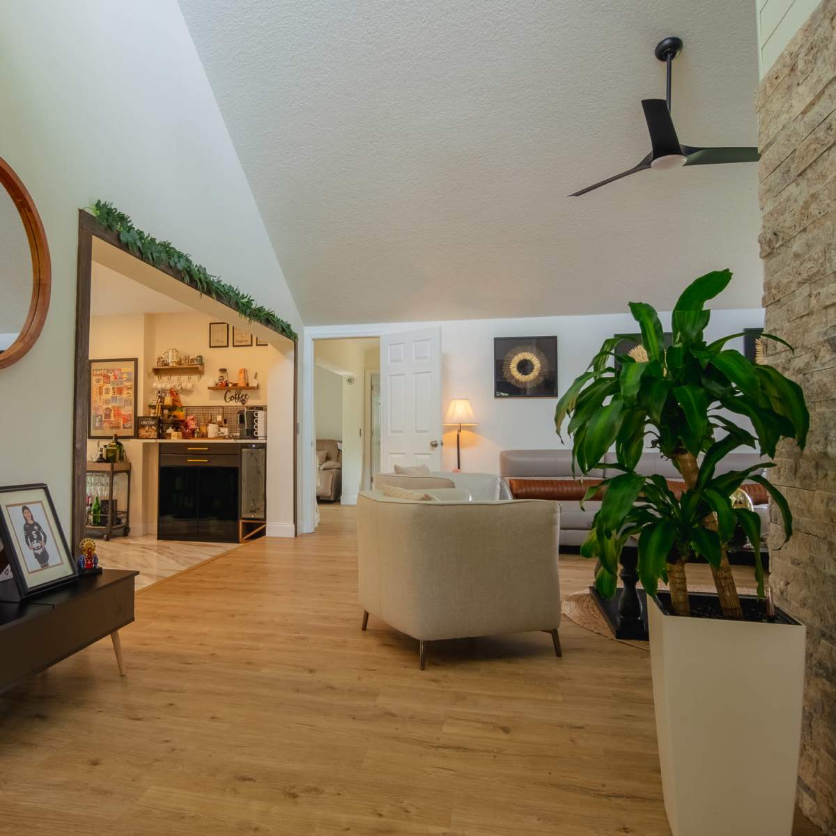 A bright, modern living space featuring a circular mirror, a potted plant, and a cozy seating area.