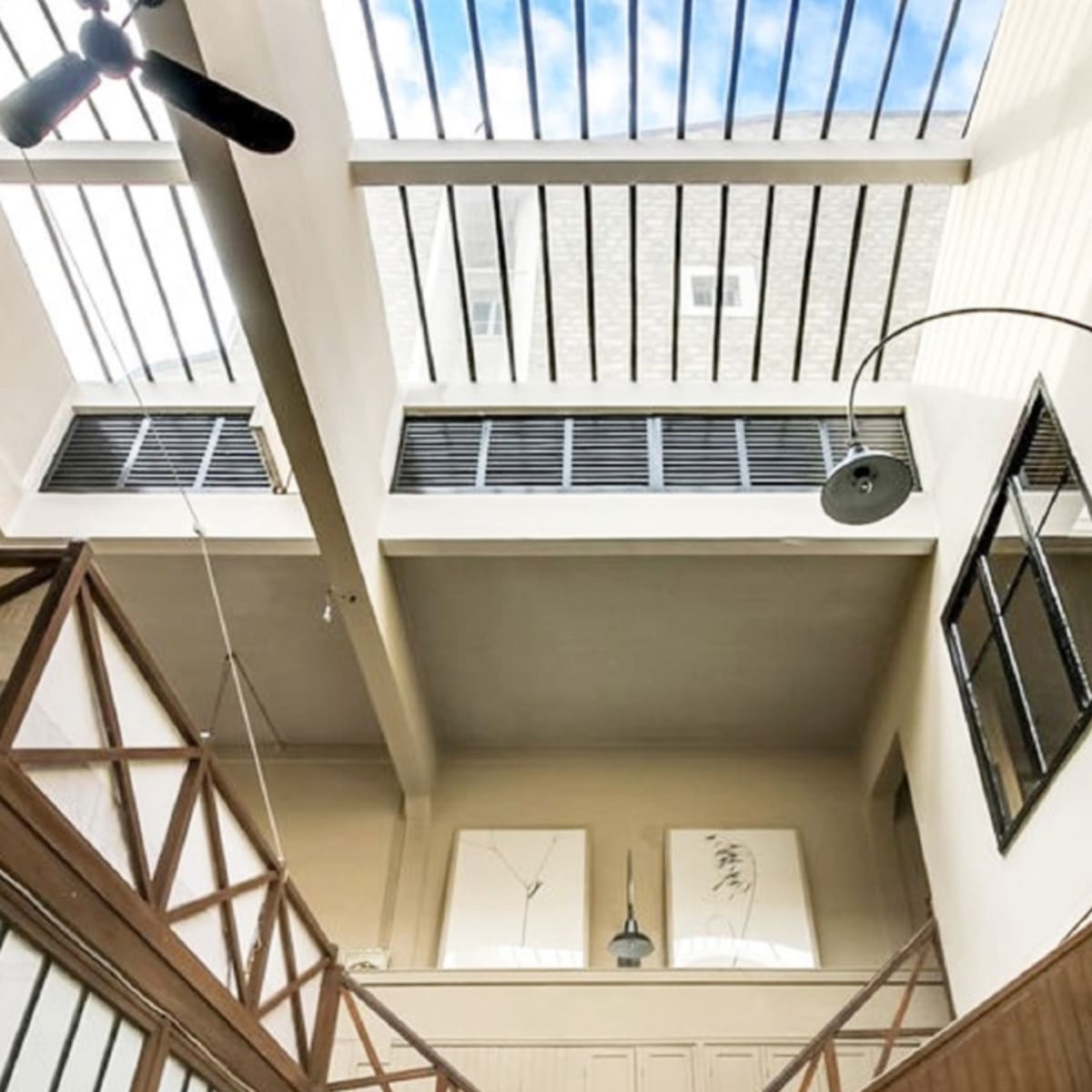 The interior of a spacious room with a high ceiling, featuring skylights and wooden architectural elements.
