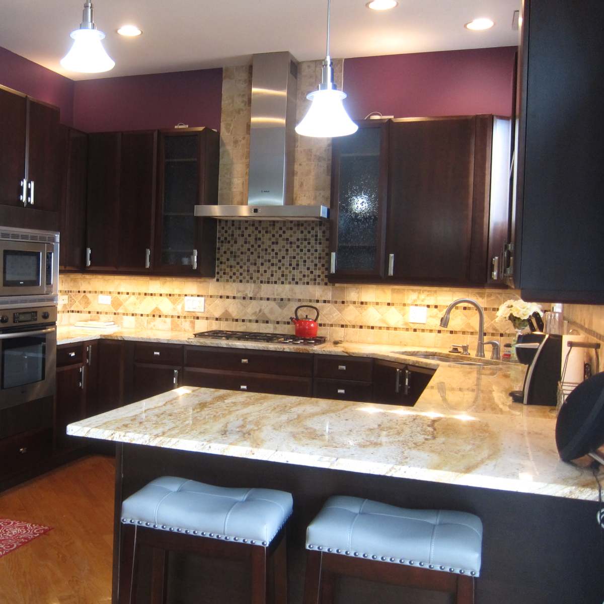 The kitchen features dark wooden cabinets, stainless steel appliances, and a granite countertop with a central island and bar seating.