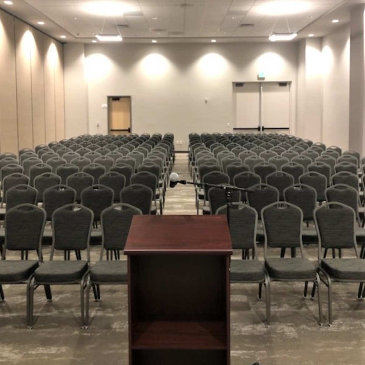 A conference room filled with rows of empty chairs and a podium at the front.