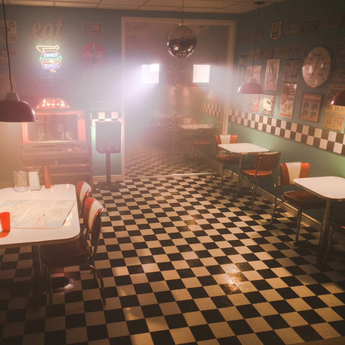 A retro diner with checkerboard floors, red vinyl booths, and dim lighting, featuring old signage on the walls.