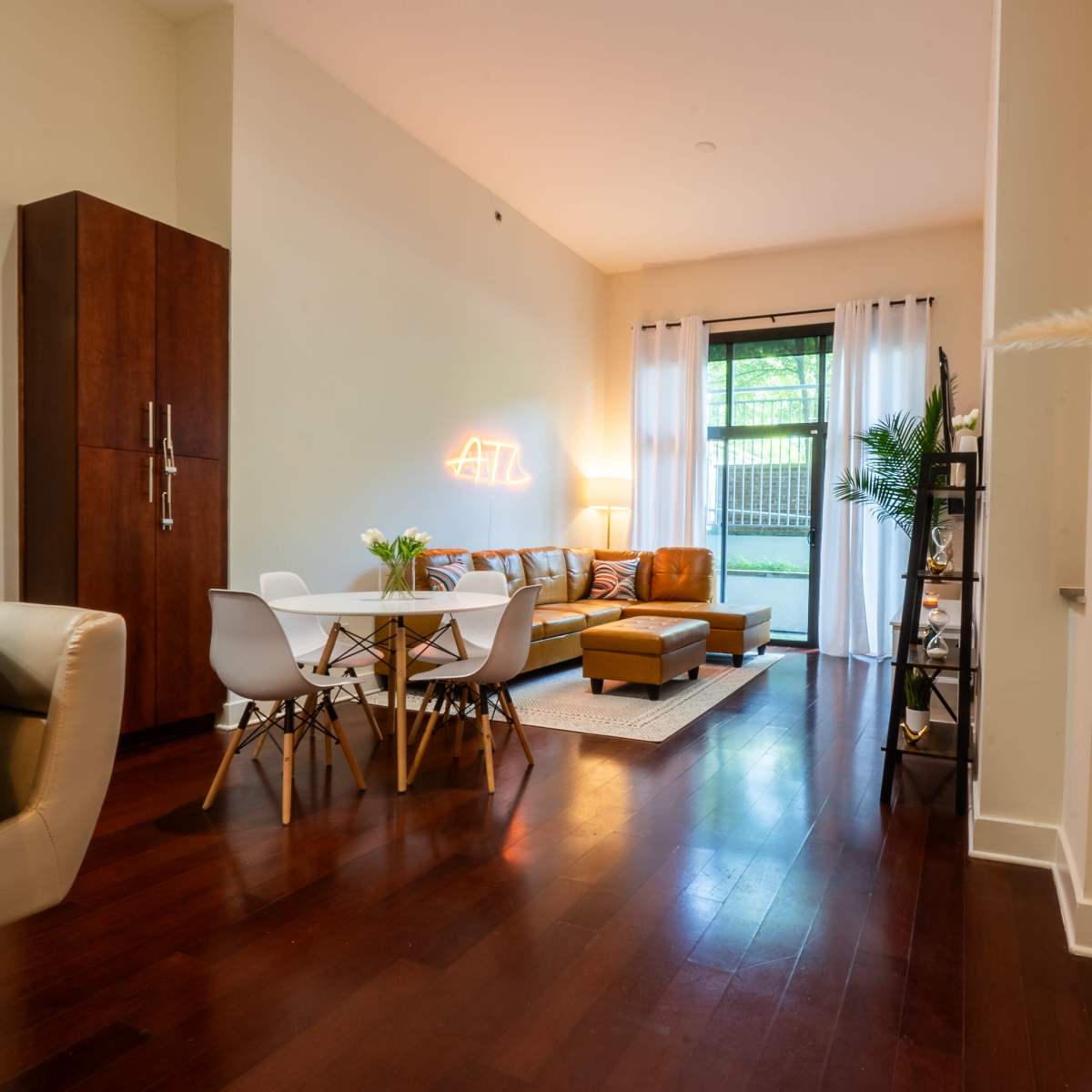 A modern living space with a dining area, a cozy sofa, and large windows allowing natural light.