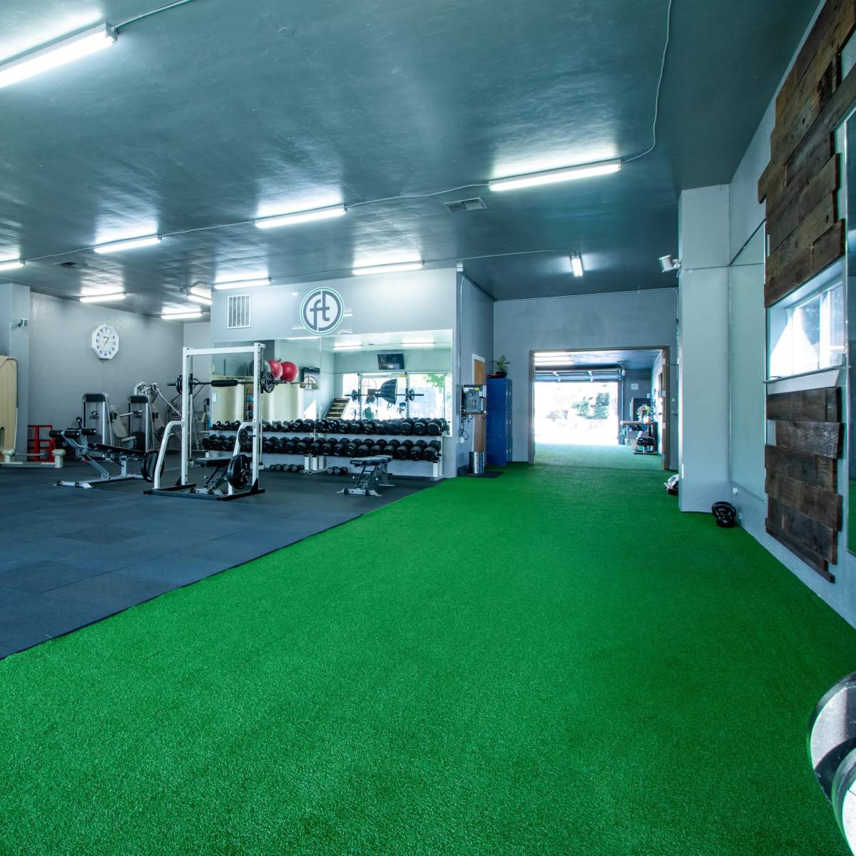 A spacious gym equipped with workout machines, free weights, and a grassy area for exercise.