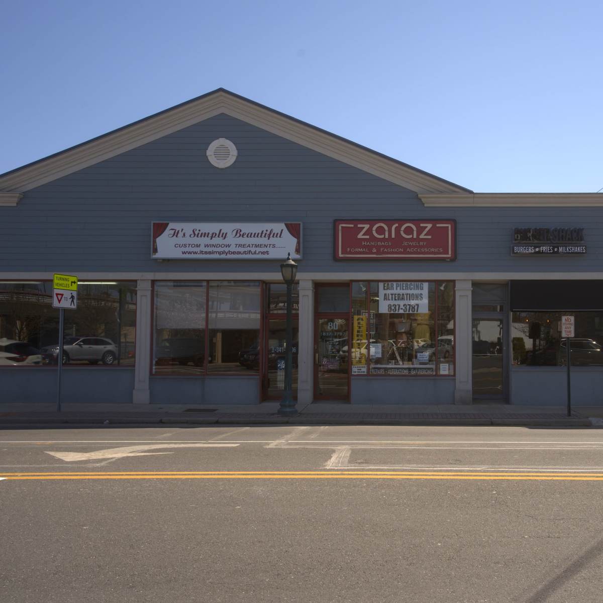 A row of storefronts along a street, featuring signs for "M's Simply Beautiful," "zaraz," and a business labeled "Café" on the right.