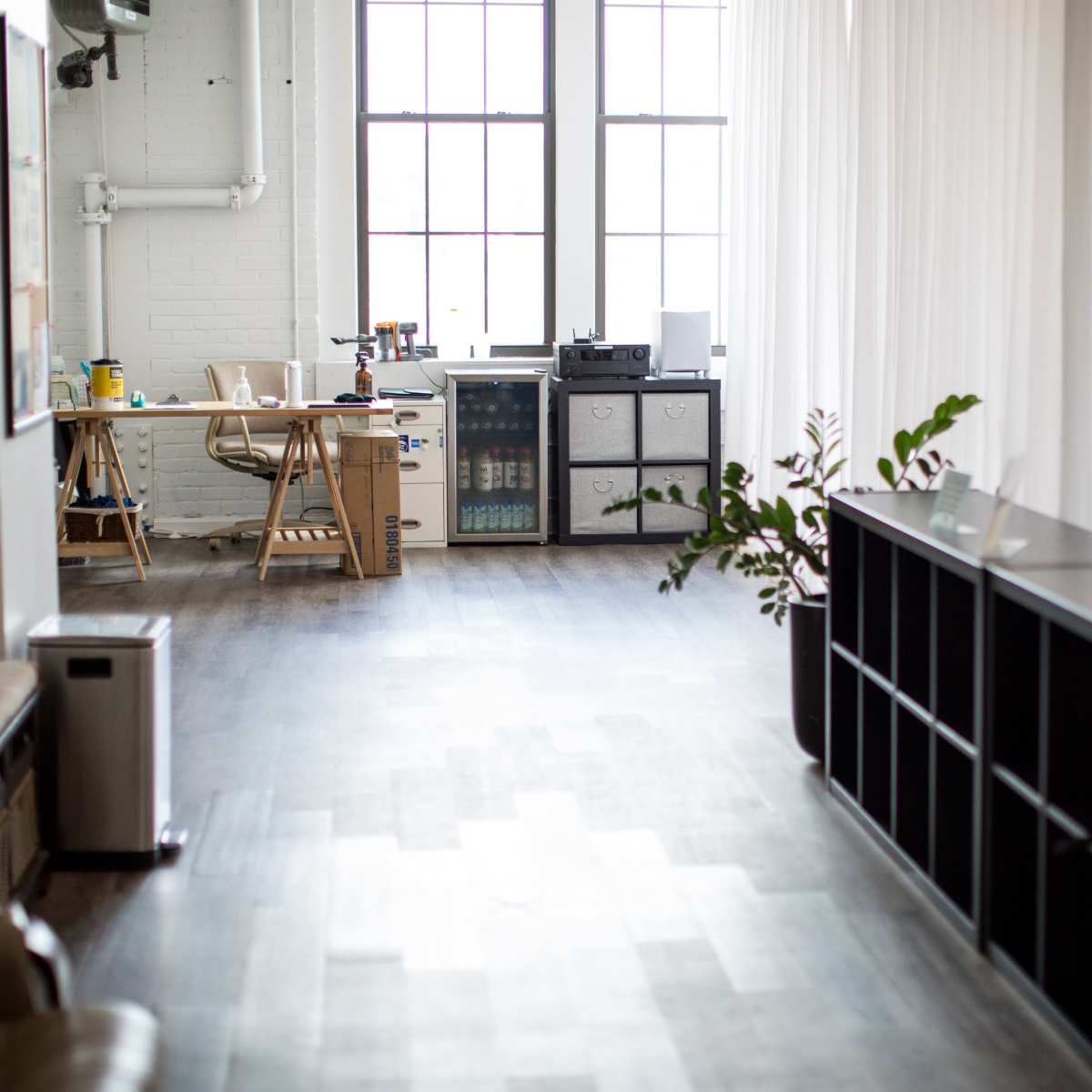 A spacious, well-lit office area with a desk, cabinets, and a plant along a hallway.