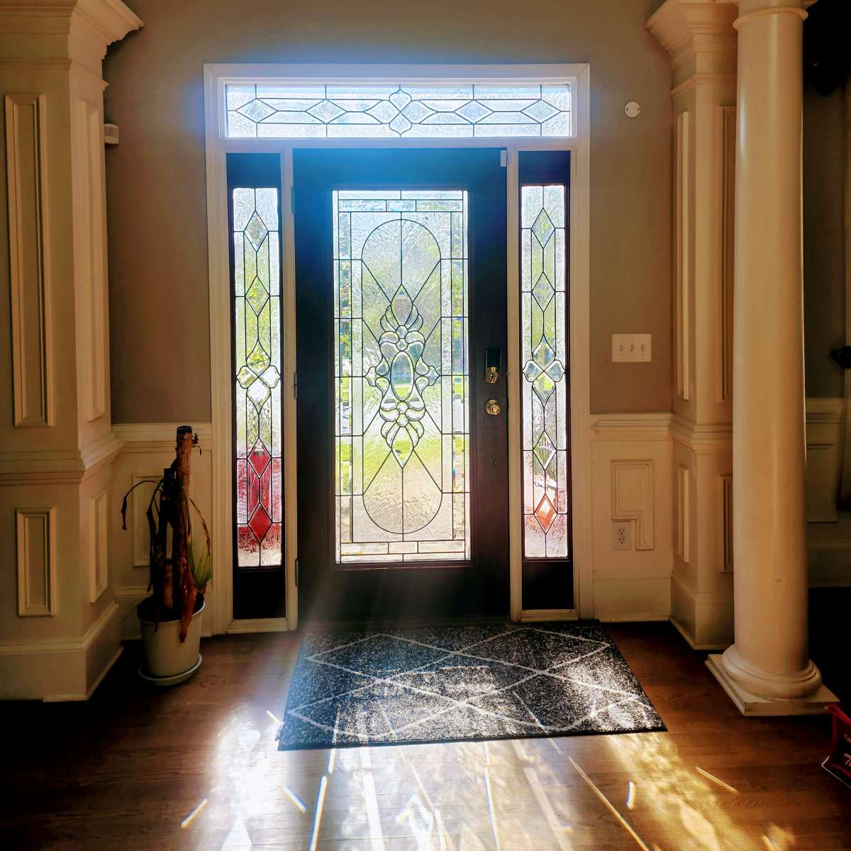 A well-lit entryway with a decorative stained glass door and columns on either side.