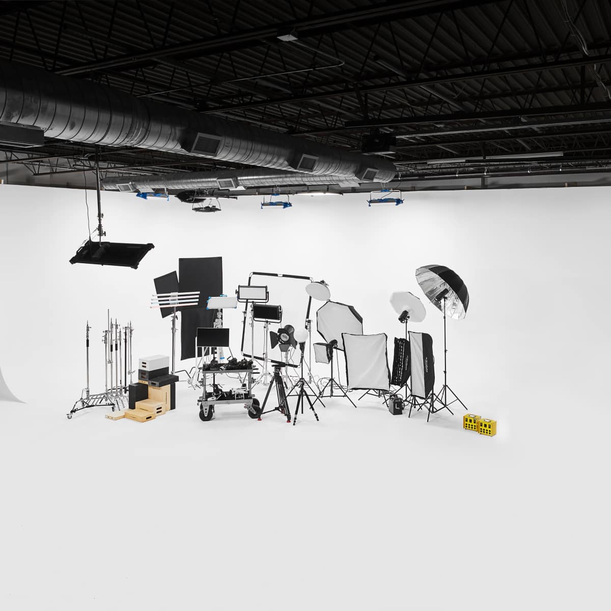 A photography studio equipped with various lighting and support equipment against a blank white backdrop.