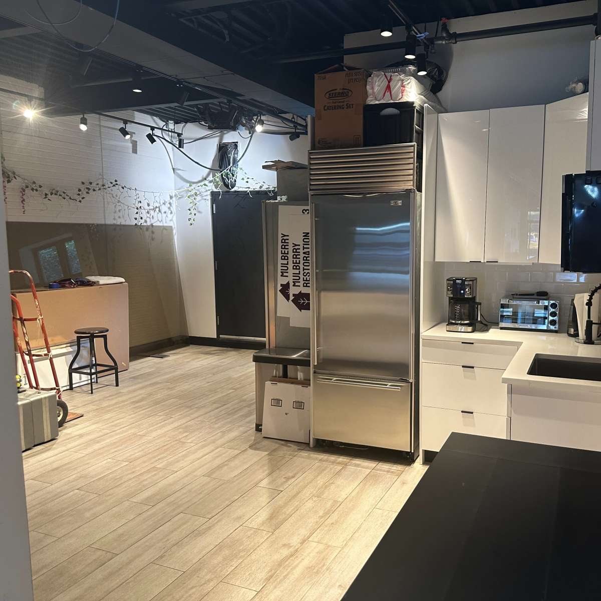 A modern kitchen with stainless steel appliances, white cabinetry, and a dark countertop.