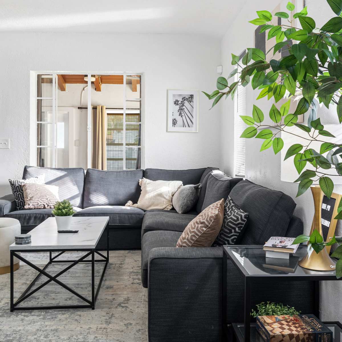 The living room features a dark sectional sofa, a coffee table, a rug, and a small side table with a decorative plant.