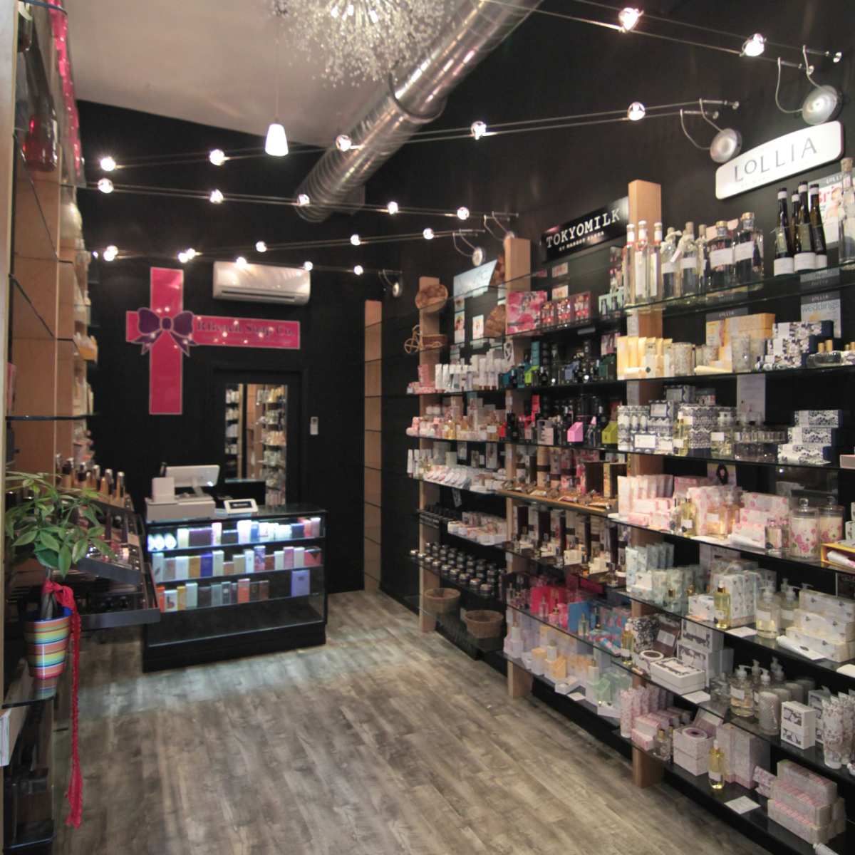 An aisle of a retail store lined with shelves of various beauty and personal care products, with display cases and decorative lighting overhead.