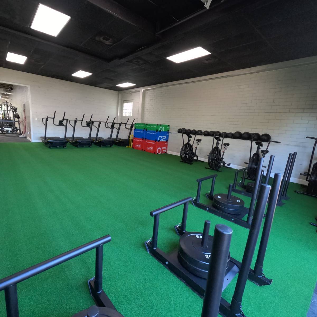 An indoor gym equipped with exercise machines, weights, and turf flooring.