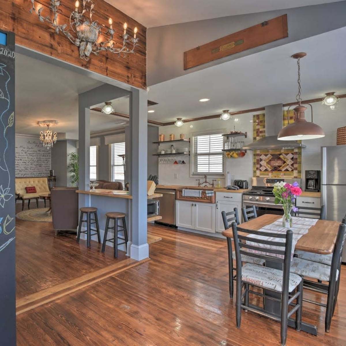 A spacious kitchen and dining area features a chalkboard welcoming guests to the "Hunt House," with wooden accents and modern appliances.