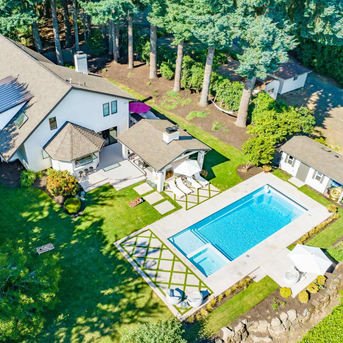 A house with a swimming pool in the backyard, surrounded by trees and landscaped green areas.
