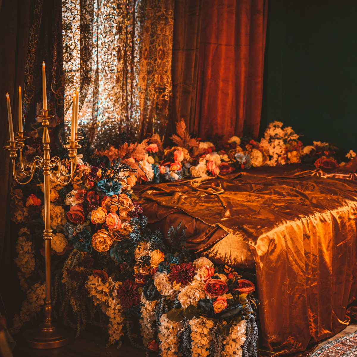 A richly decorated bedroom features a bed adorned with an ornate, flower-laden canopy and luxurious fabrics.