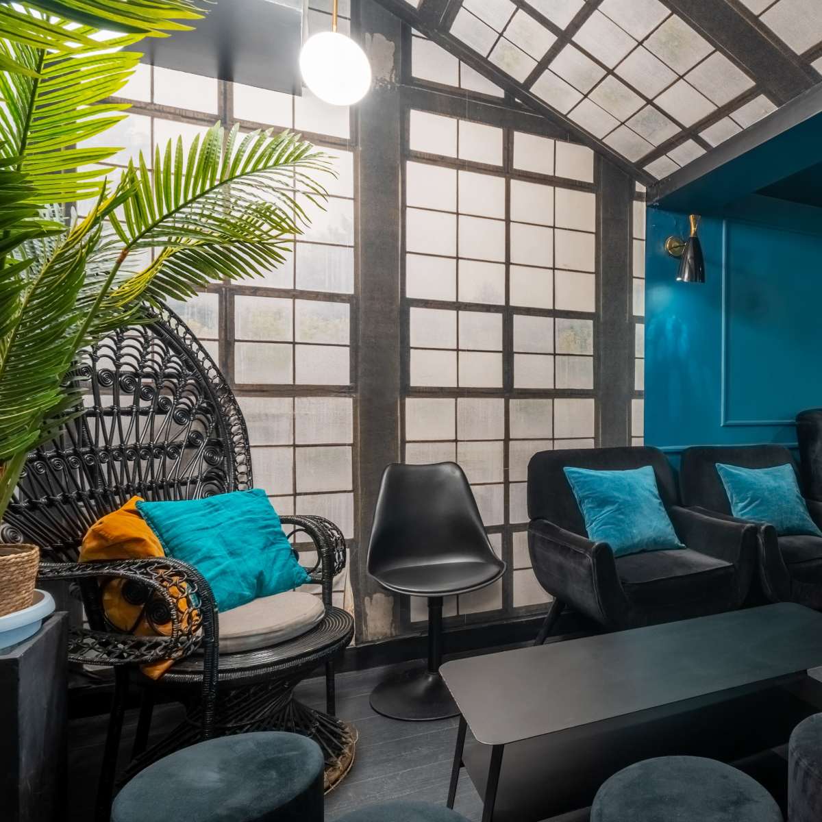 A modern lounge with dark furniture, a distinctive patterned wall, and large windows allowing natural light to fill the space.